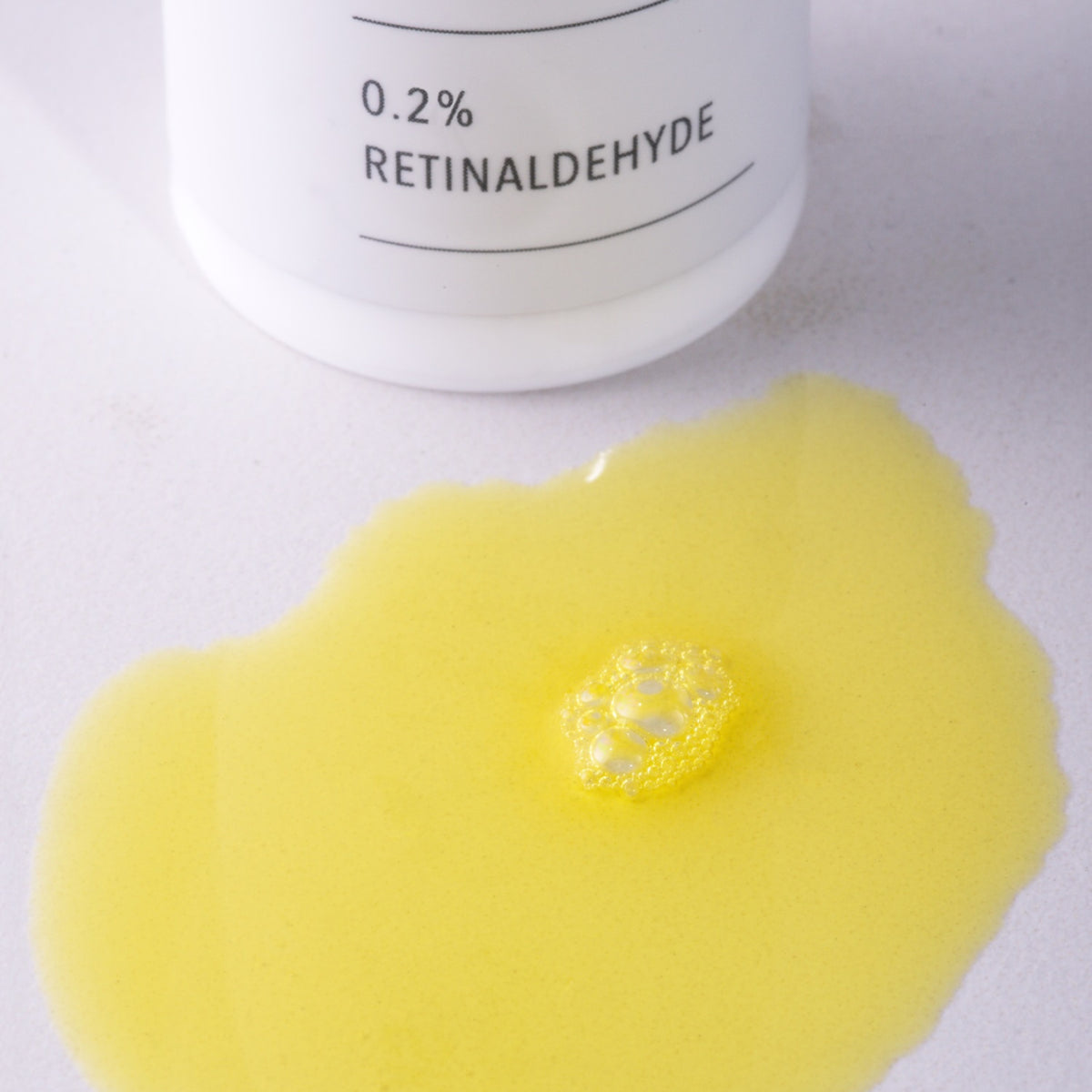 Yellow gel with a container labeled '0.2% Retinaldehyde' on a white background