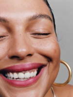 Close-up of a person with a bright smile and hoop earring