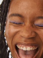 Person with a wide smile and closed eyes, with a focus on facial expression.