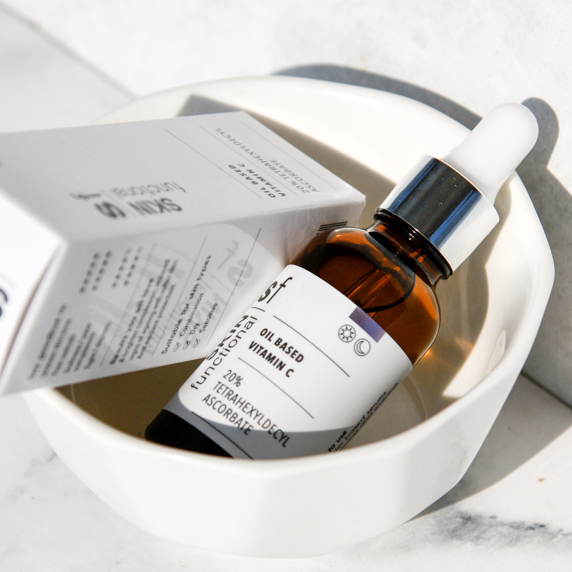 SKIN Functional Oil Based Vitamin C with details skincare product on a grey background