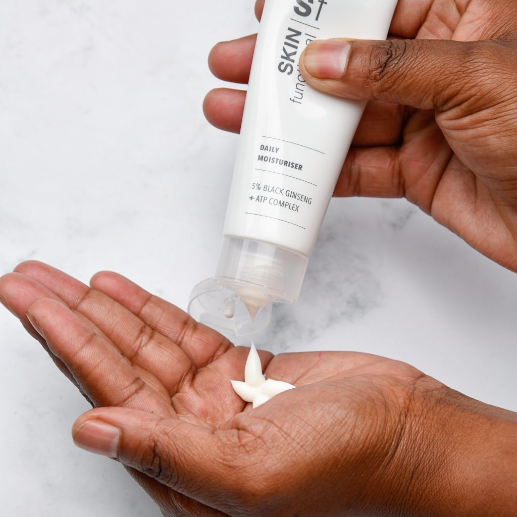 Person applying Skin Functional Daily Moisturiser product to palm with a white background