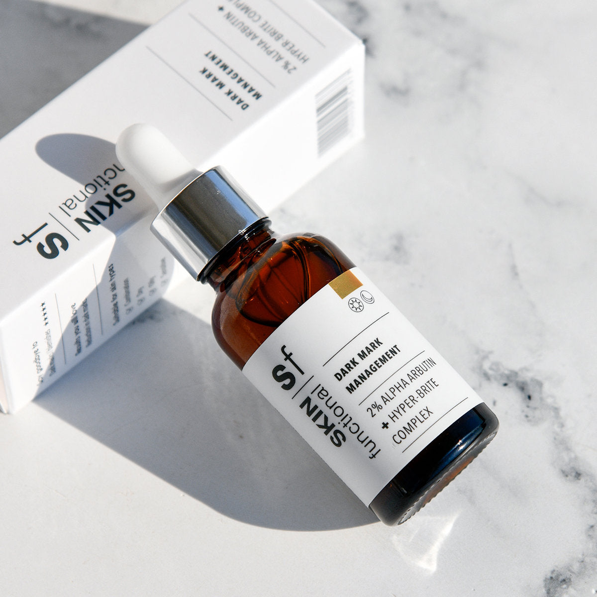 Skin Functional Dark Mark Management product with dropper and jar on a marble surface