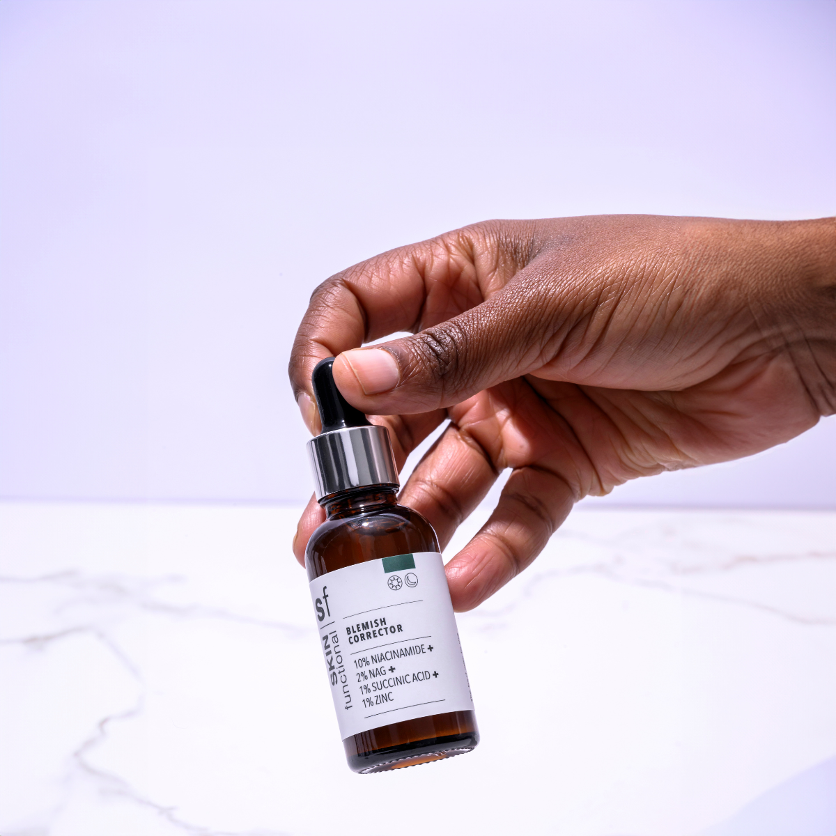 Hand holding a Skin Functional Blemish Corrector Bottle