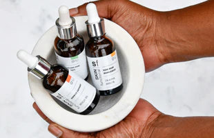 Hand holding a white dish with pigmentation control products 