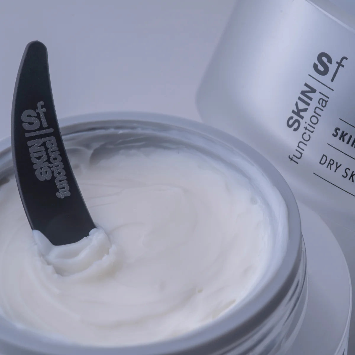 Jar of cream with a black applicator, featuring 'SKIN functional' branding.